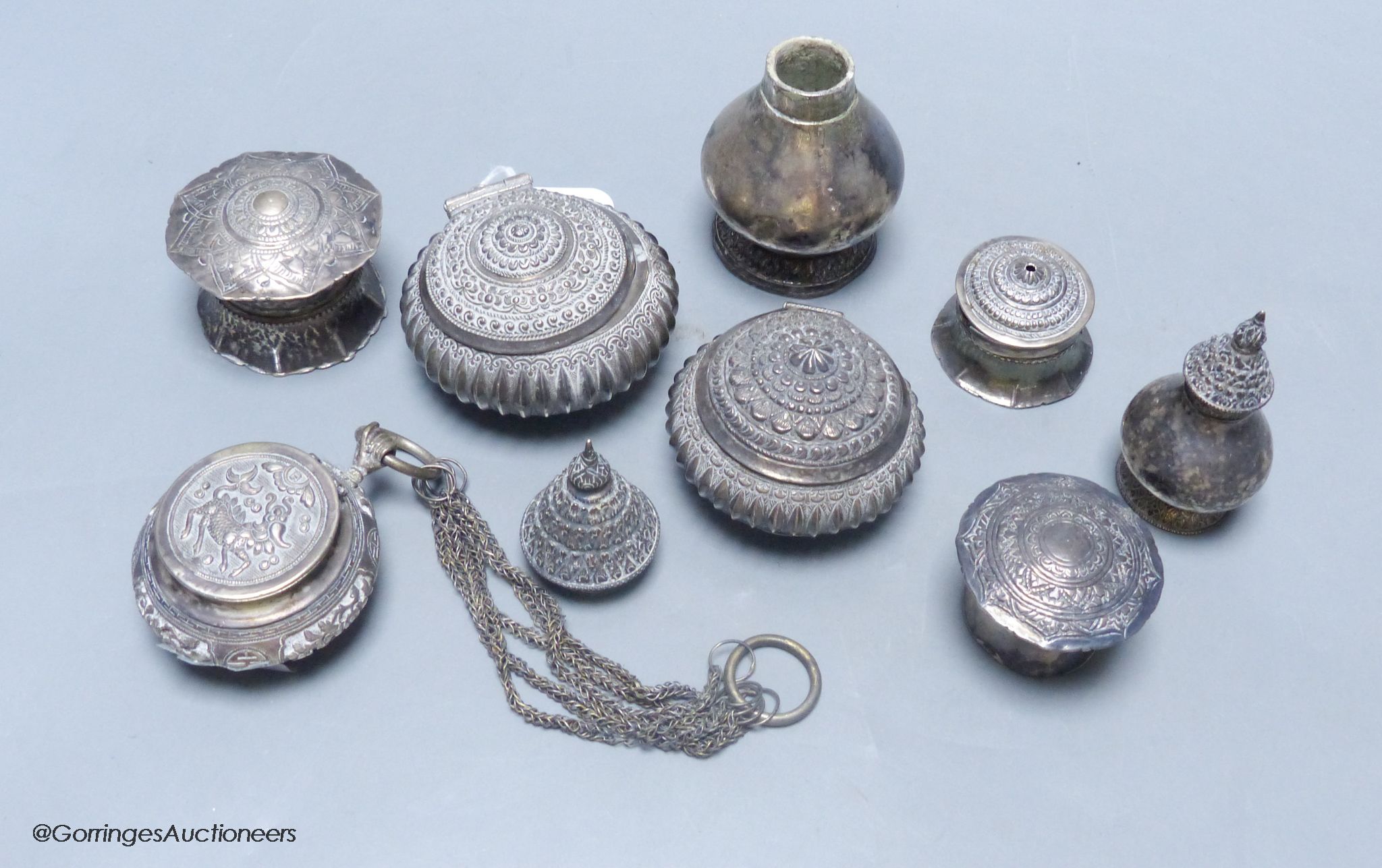 A Chinese white metal circular box and cover with multi-chain suspension, two Malay Straits white metal tobacco boxes ('Chelpa') and five similar lime boxes and covers